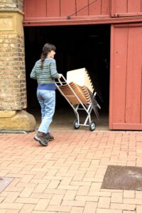 Stühle Stellen Ein Stapel Stühle wird mit dem Stuhlwagen in die Deele geschoben