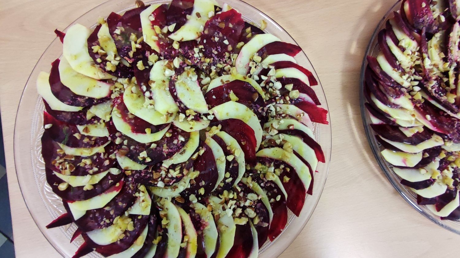Rote Bete- Apfel-Carpaccio angrechtite auf einer Glasplatte mit Walnüssen garniert