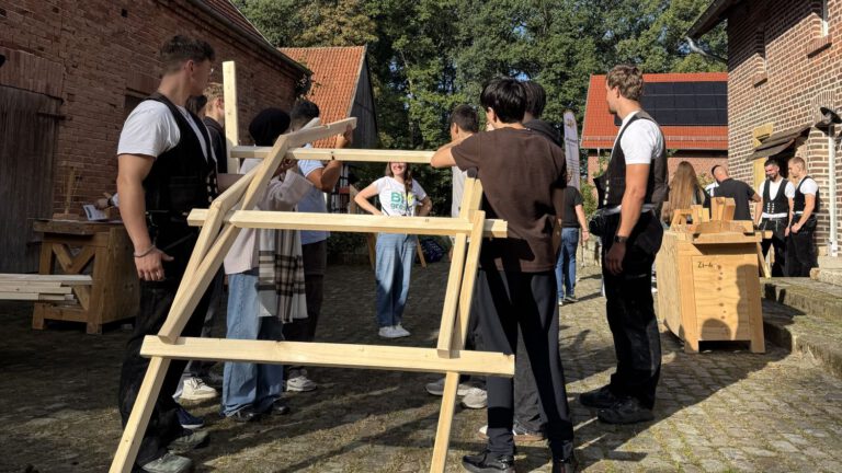 Mehrere Jugendliche bauen unter Antleitung von Zimmerern einen selbsttragenden Holzbogen aus einfachen Kanthölzern